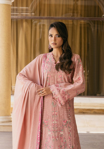 Woman wearing a pink embroidered outfit with a matching dupatta in an indoor setting.