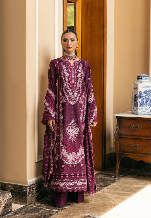 Woman in a purple embroidered dress standing in a room with a wooden door and decorative cabinet.