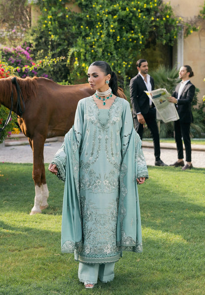 Woman in a light blue embroidered traditional outfit standing in a garden with a horse and two men in the background.