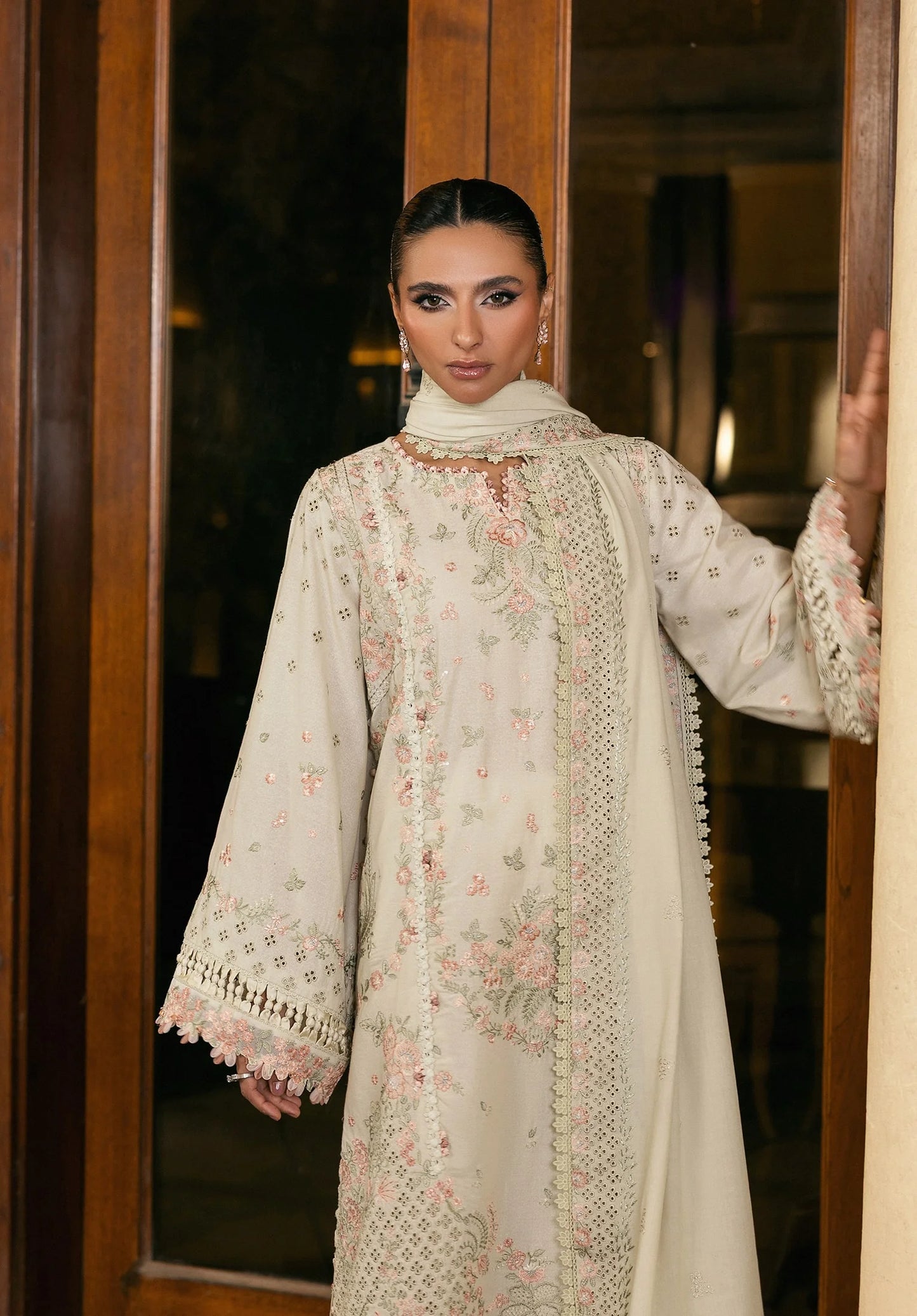 Woman wearing a light-colored embroidered traditional outfit standing indoors from elaf LUXURY WINTER '25
